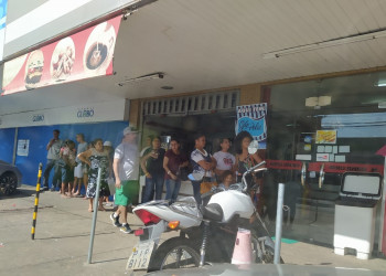 População usa entrada de padaria para fugir do sol enquanto espera ônibus no Centro